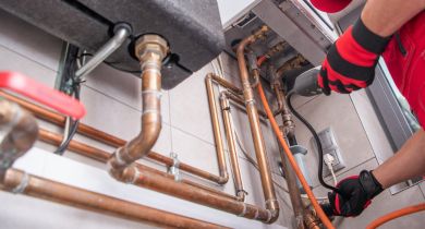 A qualified technician servicing the copper pipes of a gas hot water system