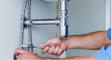 A plumber from Hydrofix Plumbing connecting a braided stainless steel water hose under a sink